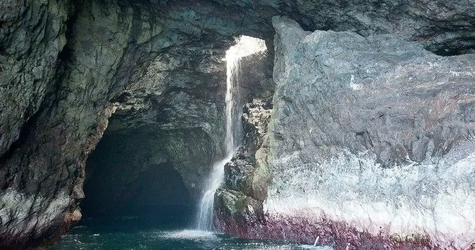 Waterfall pouring into a Nā Pali sea cave